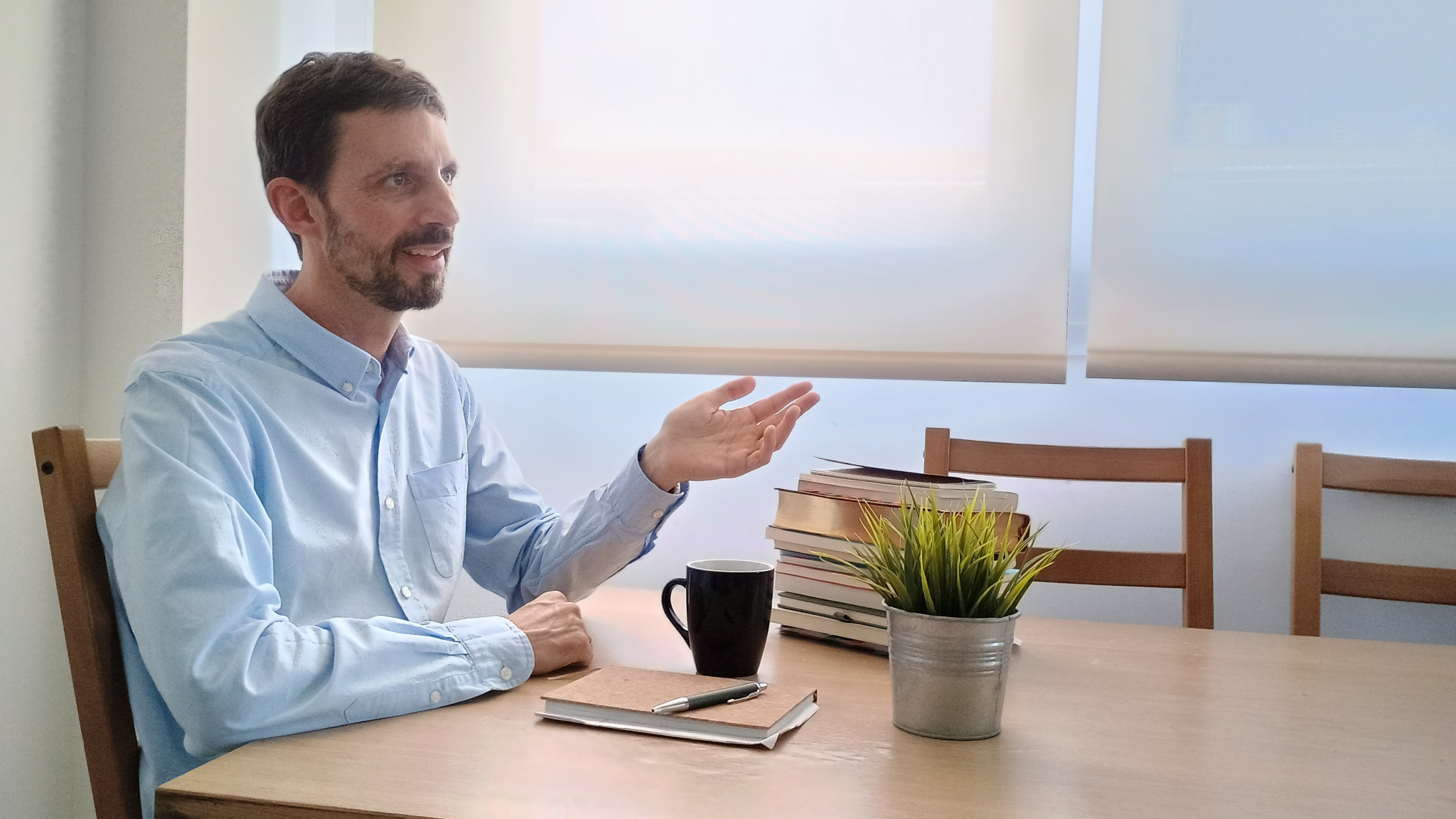 Miguel Palomo conversando en una mesa con libros y café
